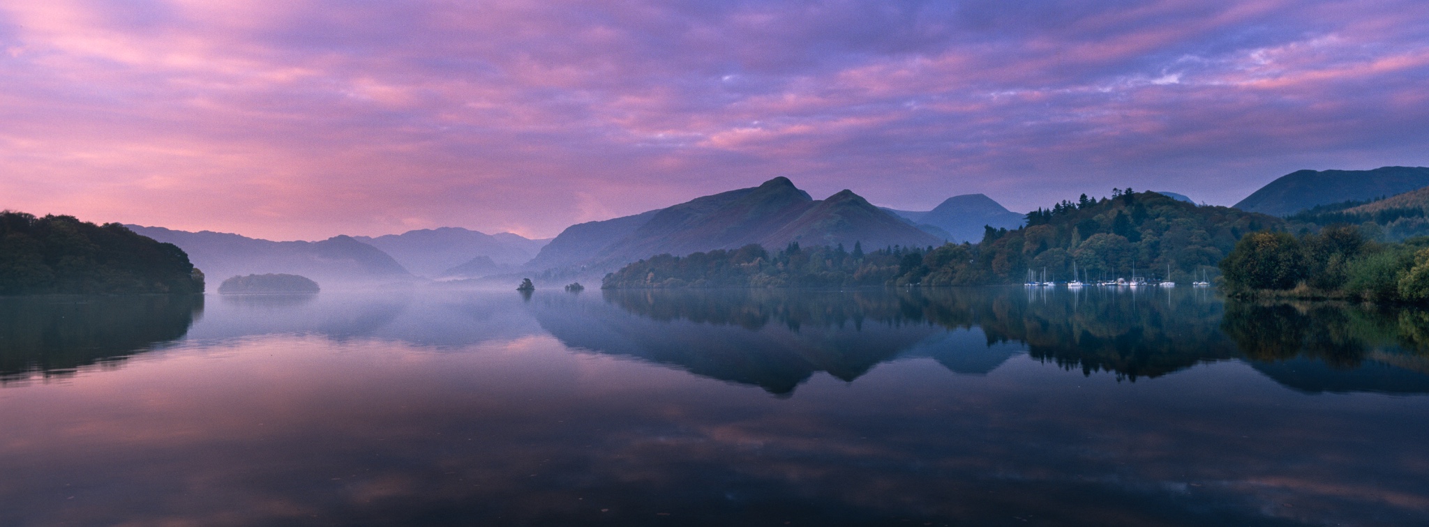 ENGLANDCumbriaLakeDistrictNationalPark.ThepastelcoloursofdawnreflectedinthestillwatersofDerwentwater