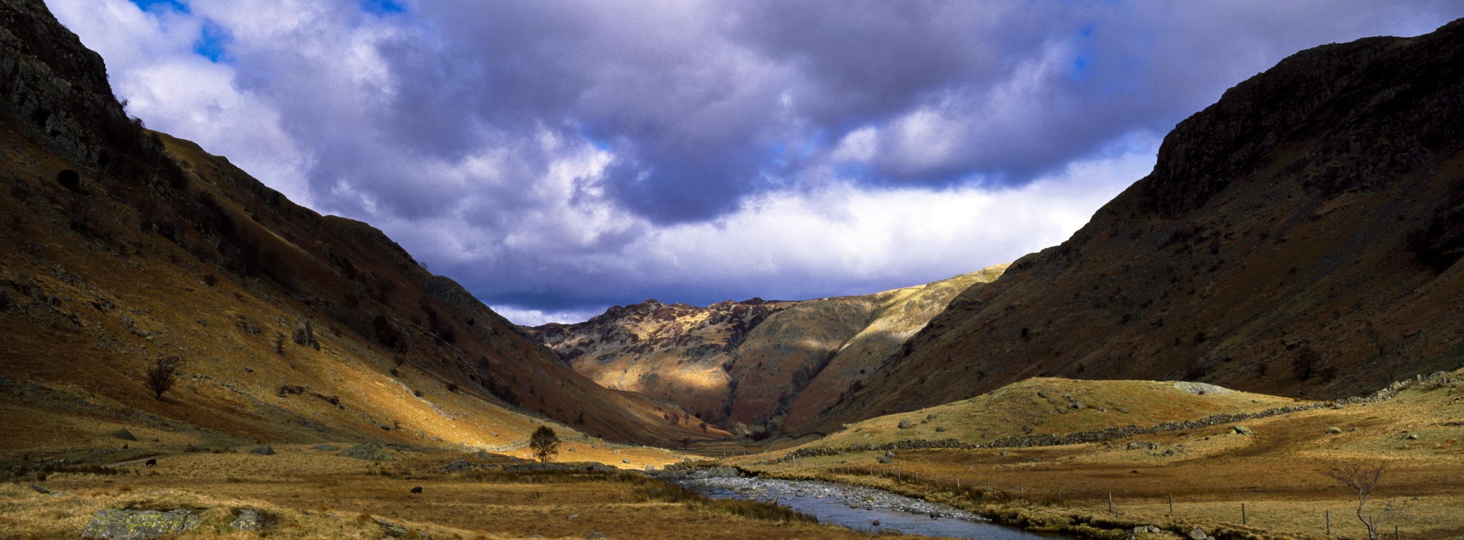 EnglandCumbriaLakeDistrictNationalPark.BriefshaftsofsunilluminatethesurroundingpeaksoftheLangstrathValley